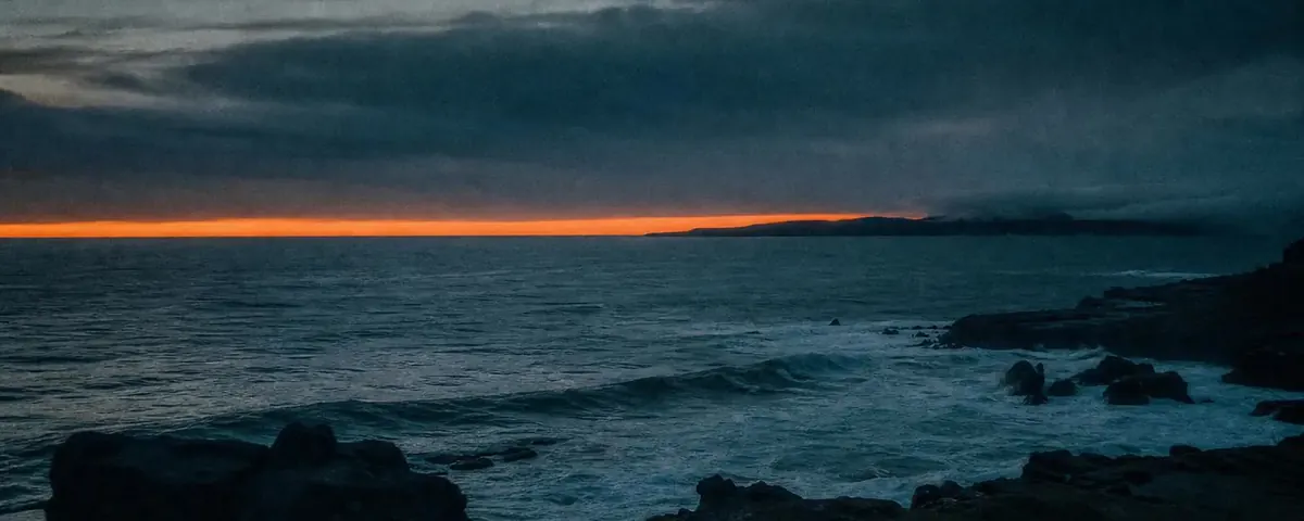 Last light of sunset settling over dark, calm water
