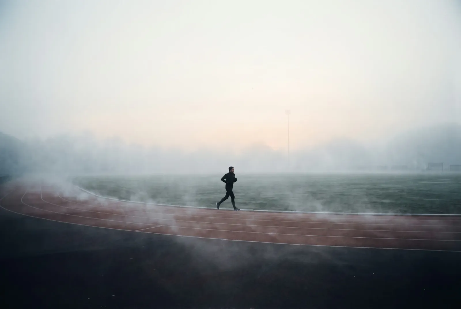 A lone runner on a misty track at first light